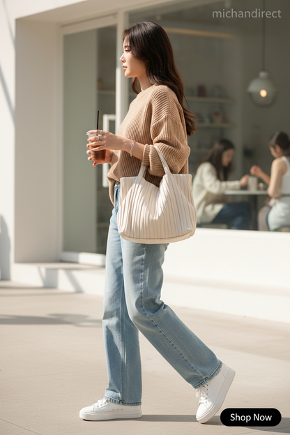 Woman in Korean fashion outfit carrying pleated tote bag with iced coffee in trendy urban setting